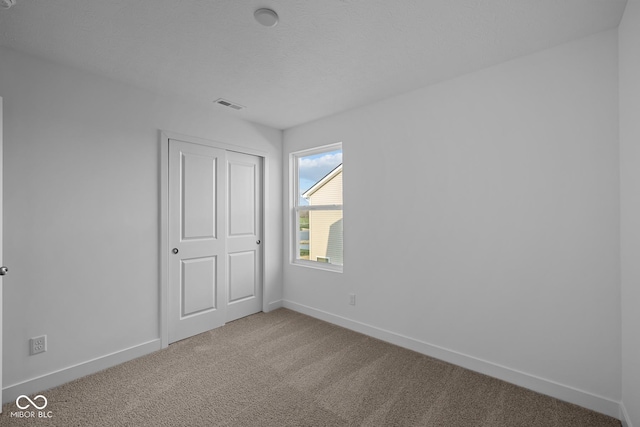 unfurnished bedroom with a closet, baseboards, carpet flooring, and visible vents