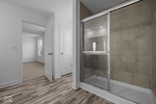 full bathroom with baseboards, a tile shower, and wood finished floors