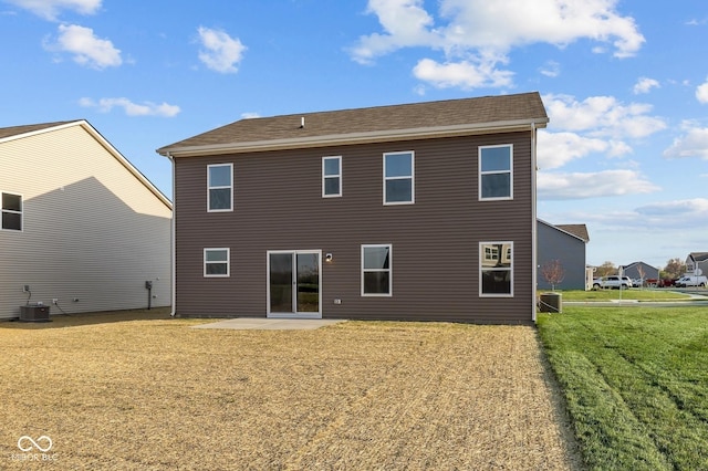 rear view of house featuring a patio, a shingled roof, a yard, and cooling unit