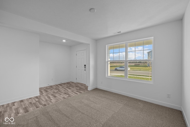 spare room featuring carpet flooring, recessed lighting, baseboards, and visible vents