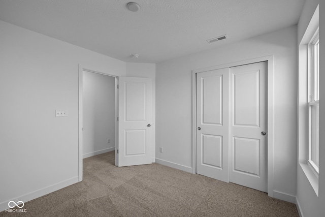 unfurnished bedroom with visible vents, carpet flooring, baseboards, and a closet
