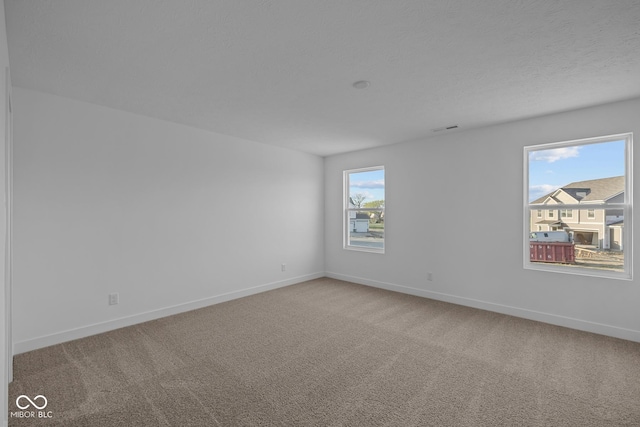 spare room featuring carpet floors and baseboards