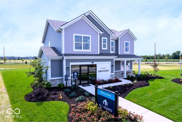 craftsman inspired home featuring board and batten siding, stone siding, and a front lawn