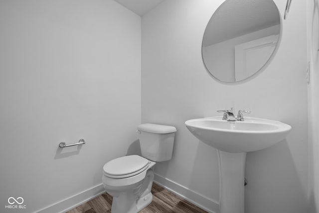 bathroom with baseboards, wood finished floors, and toilet