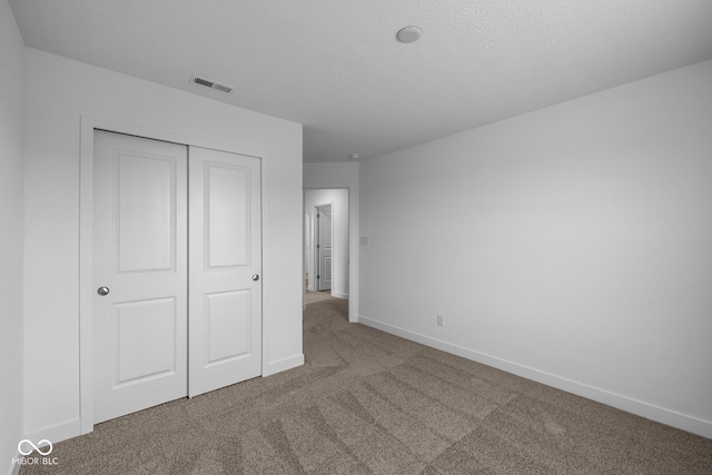 unfurnished bedroom with carpet floors, baseboards, visible vents, and a closet