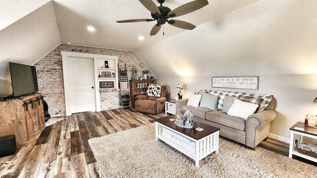 living room featuring wood finished floors, brick wall, baseboards, ceiling fan, and vaulted ceiling
