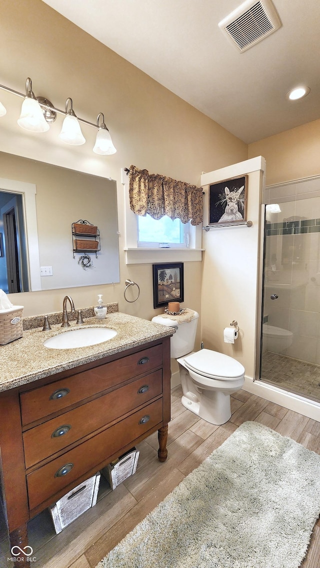 full bathroom with visible vents, vanity, wood finished floors, toilet, and a stall shower