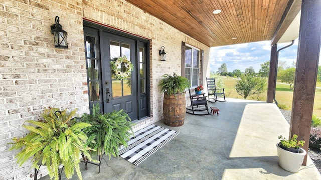 view of exterior entry featuring a porch and brick siding