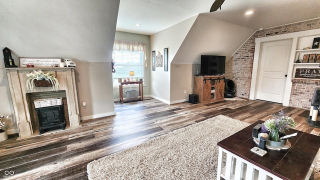 living area with wood finished floors, brick wall, a fireplace, baseboards, and recessed lighting