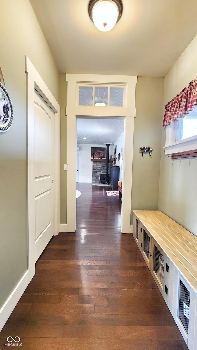 interior space with baseboards, a wood stove, and dark wood-style flooring