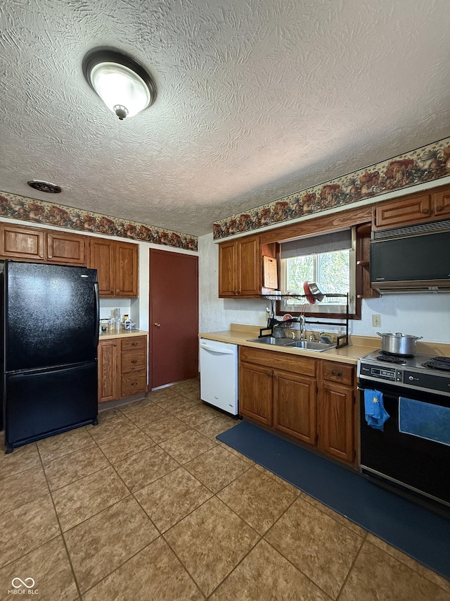 kitchen featuring a sink, light countertops, black appliances, and brown cabinets