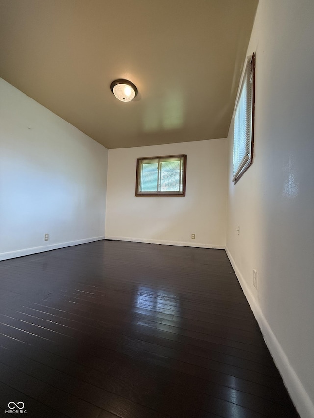 unfurnished room featuring baseboards and dark wood-style floors