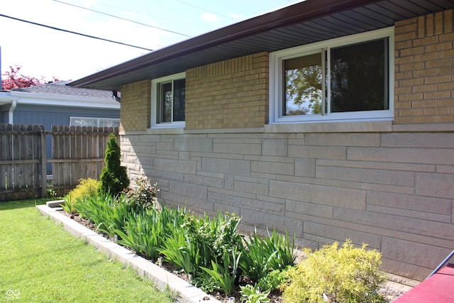 view of side of property with brick siding and fence