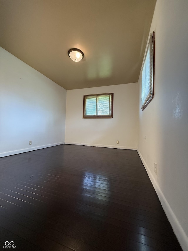 spare room with baseboards and hardwood / wood-style flooring