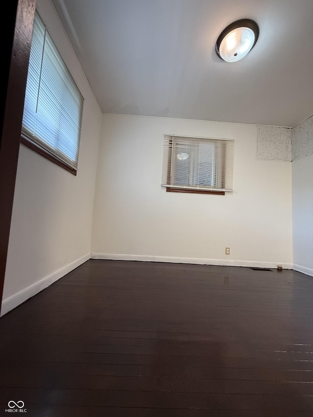 unfurnished room featuring baseboards and dark wood-style floors