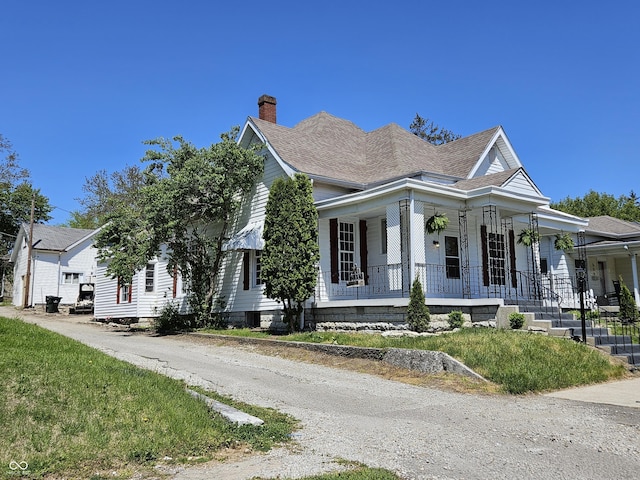 view of front of home featuring a porch, a chimney, and a shingled roof