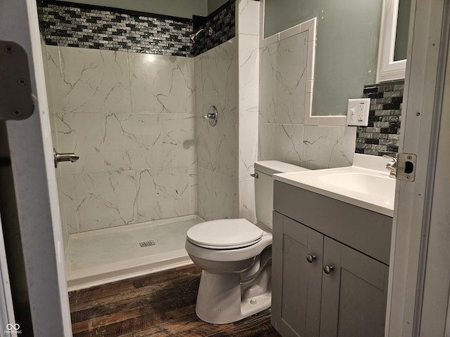 bathroom featuring tile walls, a shower stall, wood finished floors, vanity, and toilet