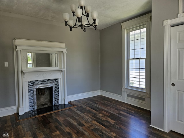 unfurnished living room with an inviting chandelier, plenty of natural light, and wood finished floors