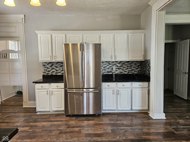 kitchen with dark countertops, white cabinets, and freestanding refrigerator