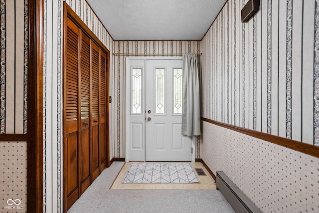 foyer with wallpapered walls, a textured ceiling, and visible vents