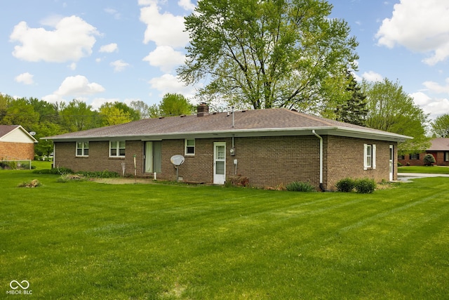 back of house with a lawn, a chimney, and brick siding