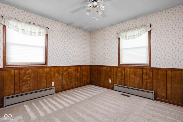 carpeted empty room with wainscoting, a healthy amount of sunlight, and a baseboard radiator