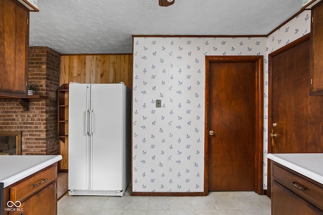 kitchen featuring crown molding, freestanding refrigerator, a textured ceiling, and light countertops