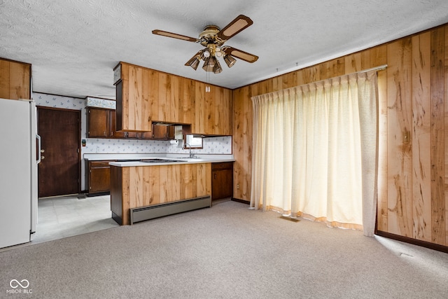 kitchen with ceiling fan, baseboard heating, light countertops, freestanding refrigerator, and a peninsula