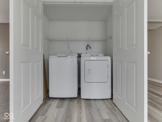 washroom with laundry area, washer and clothes dryer, light wood-style floors, and baseboards