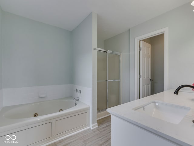 full bathroom featuring a jetted tub, a stall shower, wood finished floors, and vanity