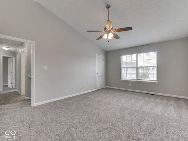 empty room featuring carpet flooring, ceiling fan, attic access, lofted ceiling, and visible vents