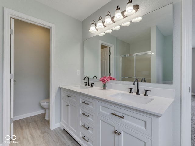 bathroom featuring double vanity, toilet, a sink, and a stall shower