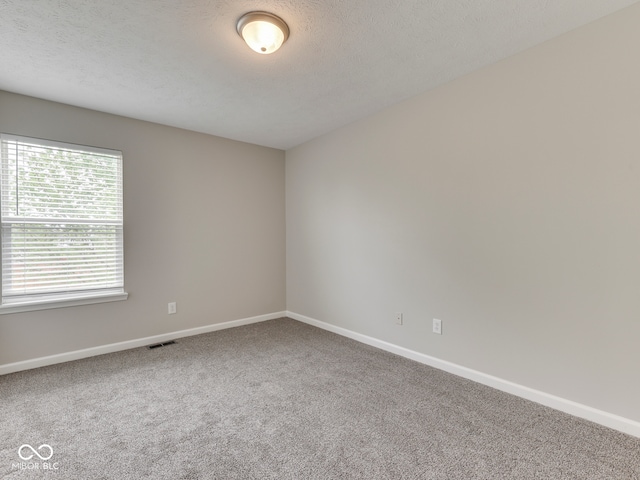 empty room with baseboards, carpet flooring, a textured ceiling, and visible vents