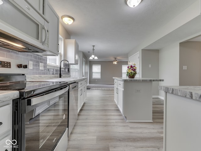 kitchen with decorative backsplash, a sink, baseboards, light wood finished floors, and stainless steel appliances