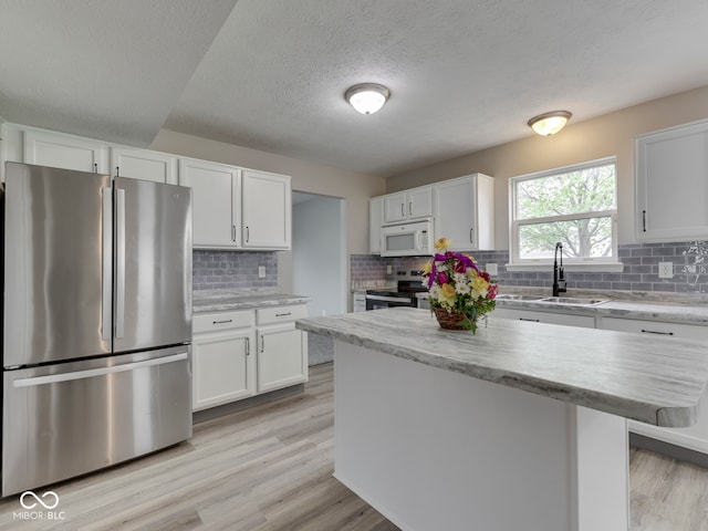 kitchen with light wood-style floors, a sink, white cabinets, and stainless steel appliances
