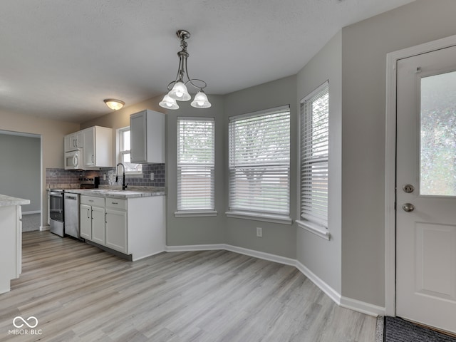 kitchen with backsplash, stove, light wood-type flooring, a sink, and light countertops