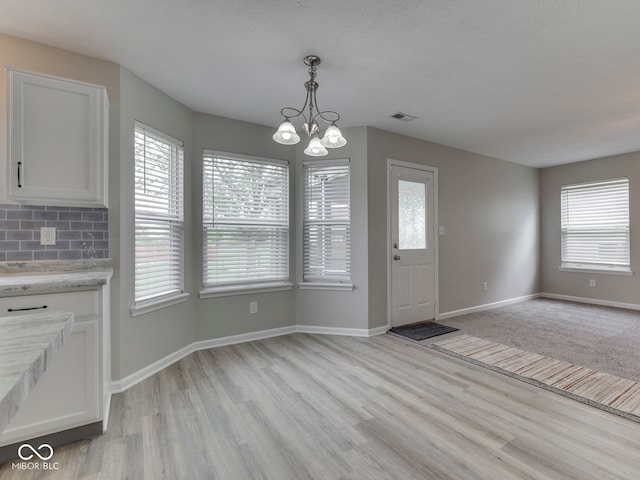 entrance foyer with plenty of natural light, light wood-type flooring, visible vents, and a chandelier