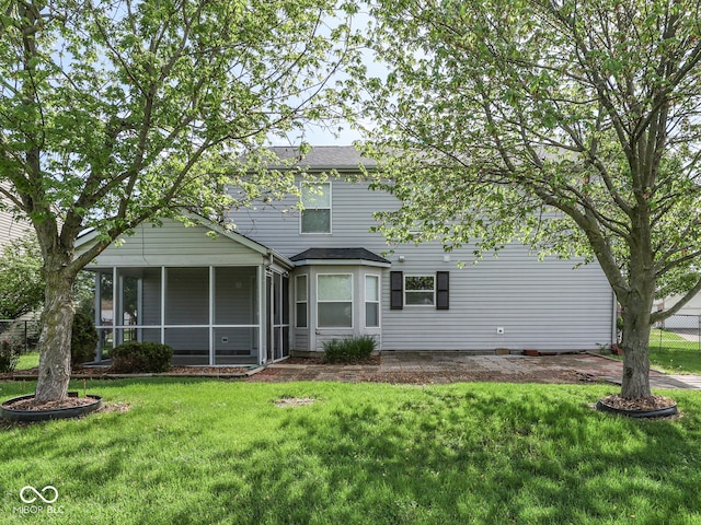view of front of house with roof with shingles, a sunroom, and a front yard