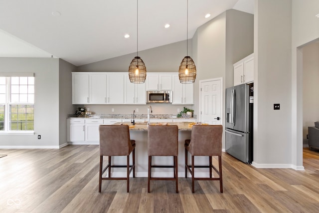 11595 Platt St, Noblesville, IN 46060 - kitchen with appliances with stainless steel finishes, baseboards, high vaulted ceiling, white cabinets, and light stone countertops