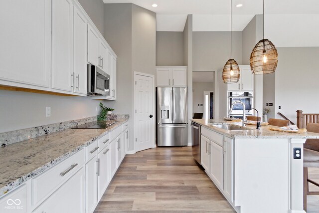 11595 Platt St, Noblesville, IN 46060 - kitchen featuring stainless steel appliances, a sink, light wood-style floors, white cabinetry, and a breakfast bar area
