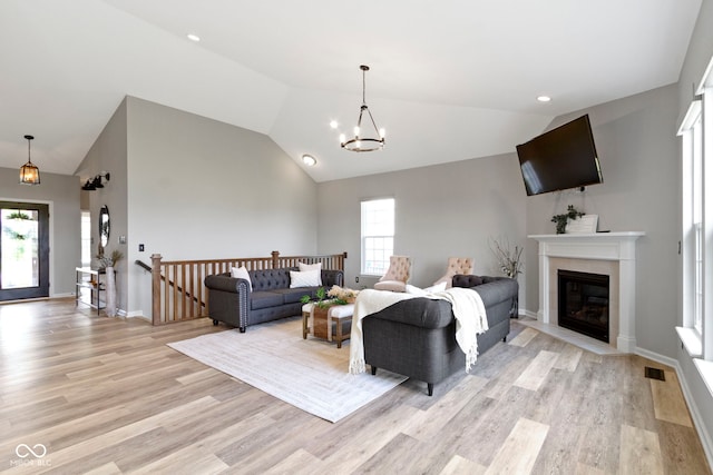 11595 Platt St, Noblesville, IN 46060 - living area featuring light wood-style floors, a chandelier, a fireplace with flush hearth, baseboards, and high vaulted ceiling