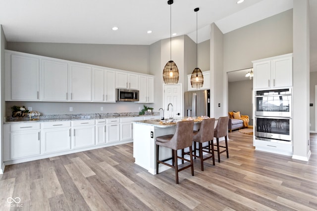 11595 Platt St, Noblesville, IN 46060 - kitchen with stainless steel appliances, high vaulted ceiling, white cabinetry, a breakfast bar, and recessed lighting