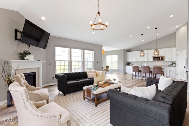 11595 Platt St, Noblesville, IN 46060 - living area with vaulted ceiling, a chandelier, light wood-style floors, a fireplace, and baseboards