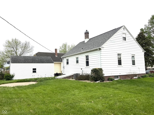 back of property featuring a lawn, a chimney, and roof with shingles