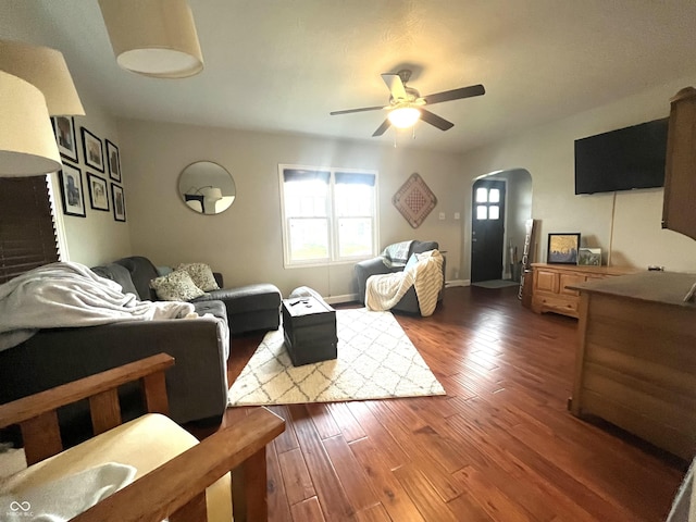 living area featuring arched walkways, ceiling fan, and wood finished floors