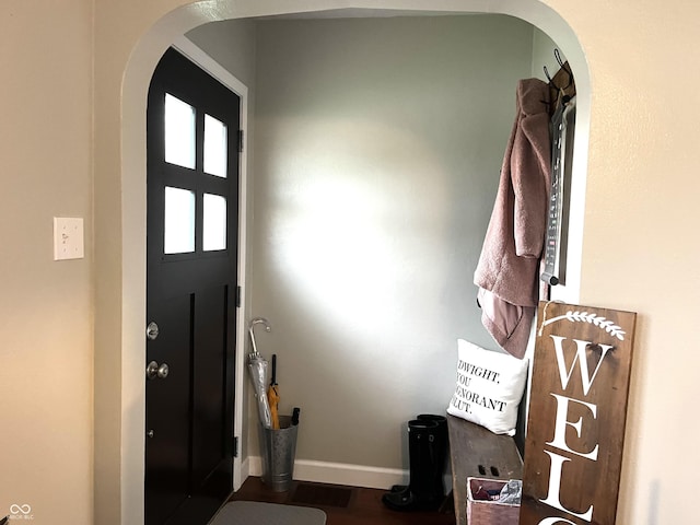 foyer entrance featuring arched walkways, baseboards, and wood finished floors