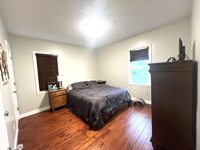 bedroom with baseboards, a textured ceiling, and wood finished floors