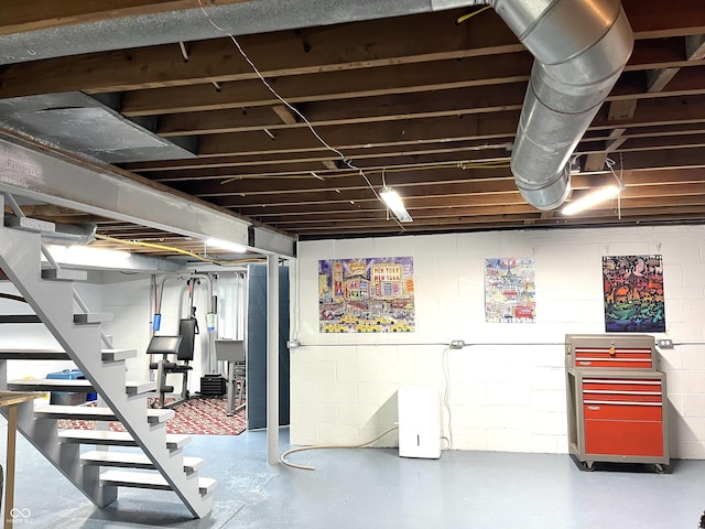 unfinished below grade area featuring stairway and concrete block wall