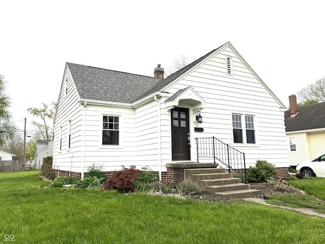 view of front of property featuring roof with shingles, a chimney, and a front yard