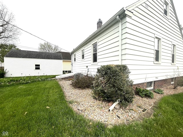 view of side of home with a yard, cooling unit, and a chimney